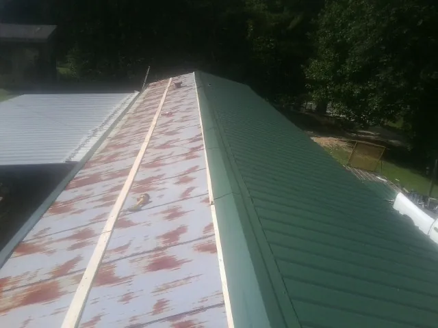 Old rusted panels beside newly installed green metal roofing — Wind Damage Roof Repair by Roofing Brothers in West Elkton