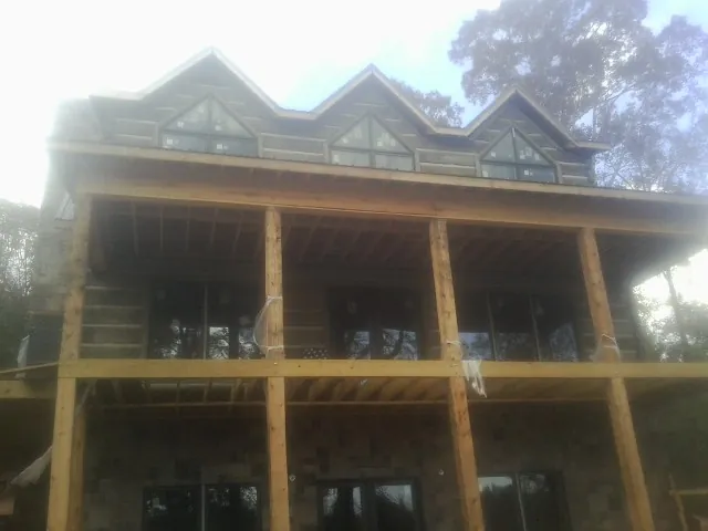 Dormers and porch framing on a large log home under construction — Roof Coating work by our crew in West Elkton