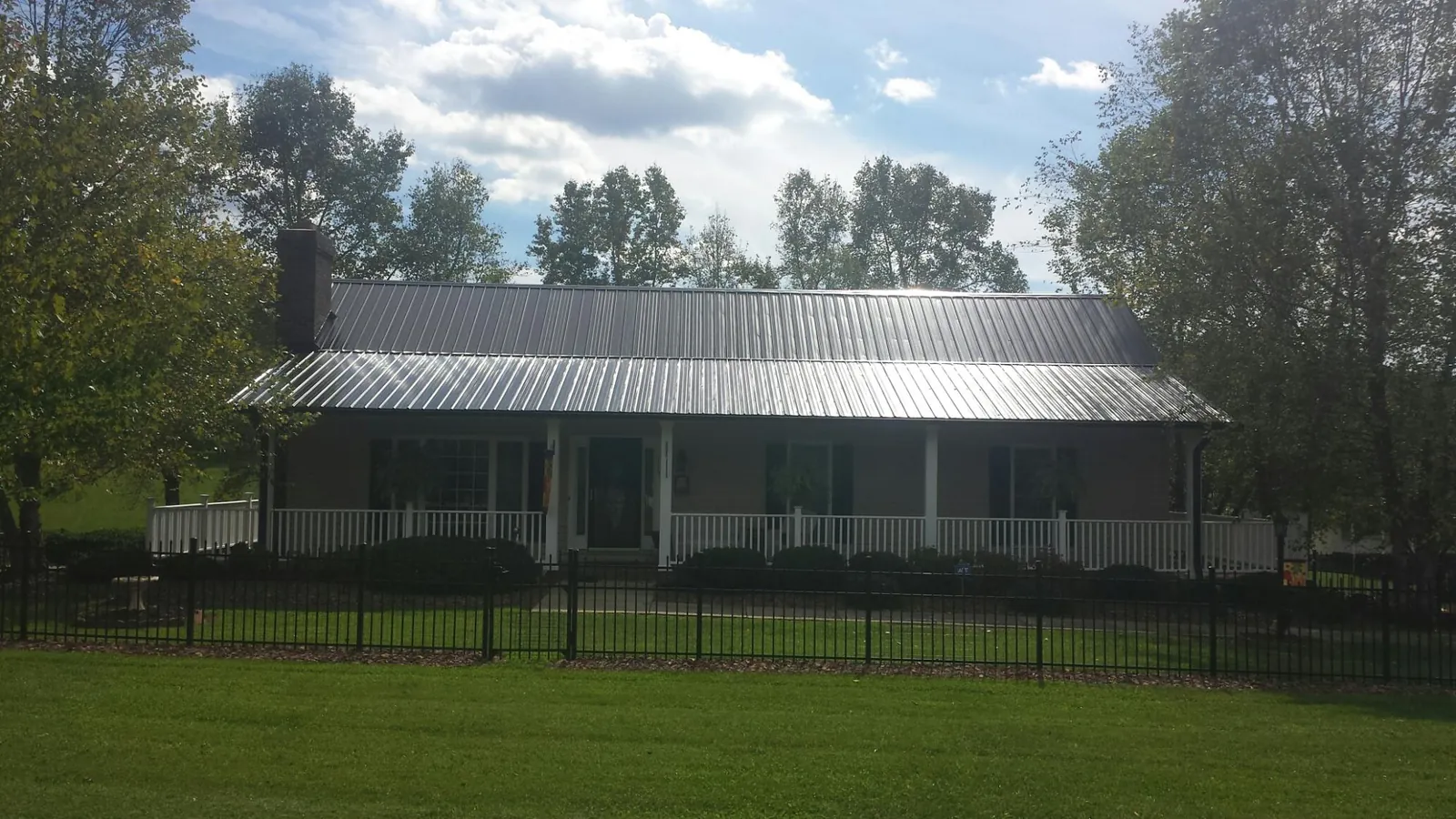 Gray metal roof on a brick ranch with a full width front porch — Gutter Guard Installation work by our crew in West Elkton