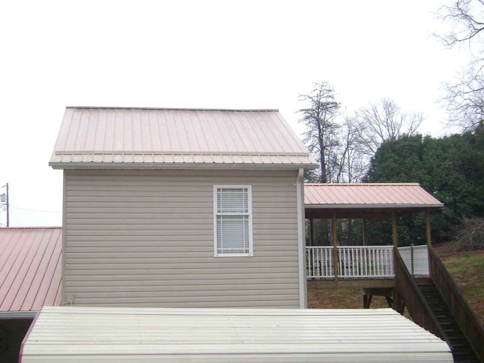 Tan metal roofs on a two story addition and attached porch, from a Roof Replacement job in West Elkton